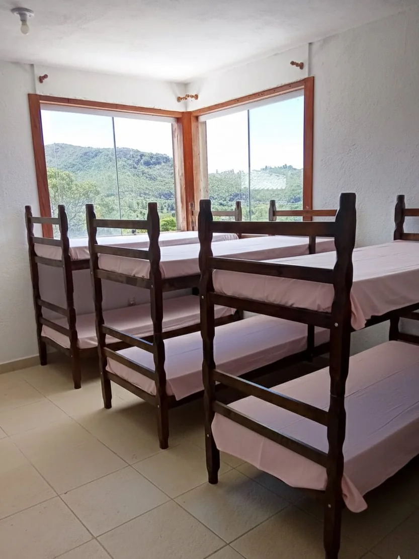 Clínica de reabilitação em Sabará - MG Quarto coletivo com beliches de madeira e janela ampla para a mata