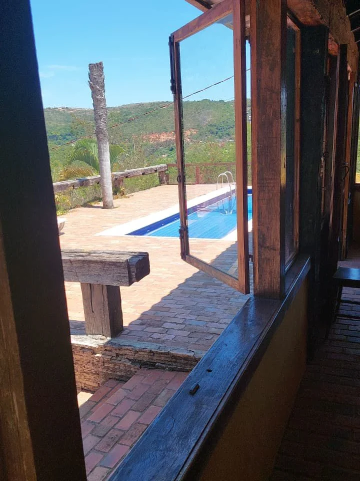 Clínica de recuperação em Sabará - MG Varanda de madeira e vidro aberta para a piscina, com a serra ao fundo